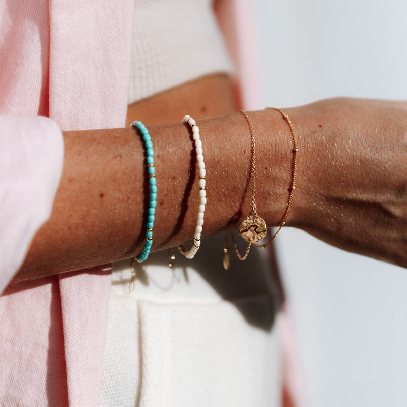 Damen Gold Armband mit Wellen Anhänger und weißes Perlen Armband. | Style: Aloita